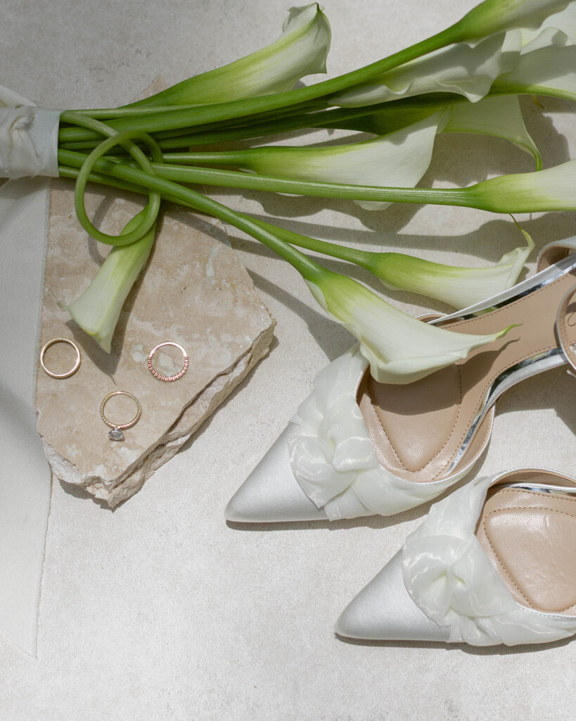 Close-up of white calla lilies, bridal shoes, and wedding rings before an Epping Forest Country Club wedding in Jacksonville