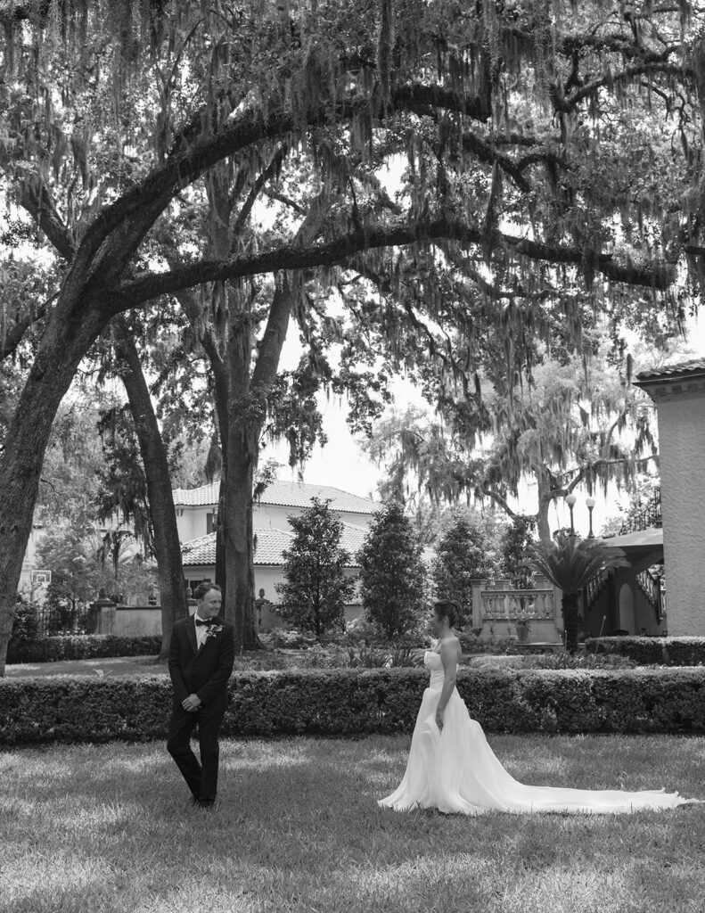 Black and white portrait of the bride walking beneath oak trees at Epping Forest Yacht & Country Club in Jacksonville, Florida