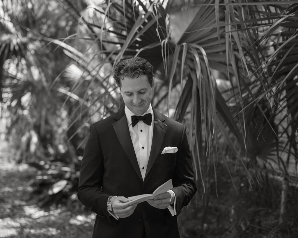 Groom reading his vows beneath palm fronds before the St. Augustine, Florida wedding