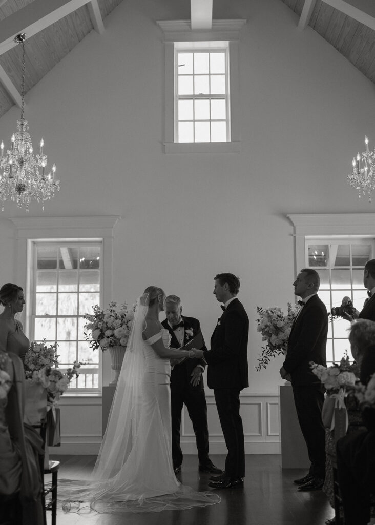 Black and white photo of the wedding ceremony beneath chandeliers, St. Augustine, Florida