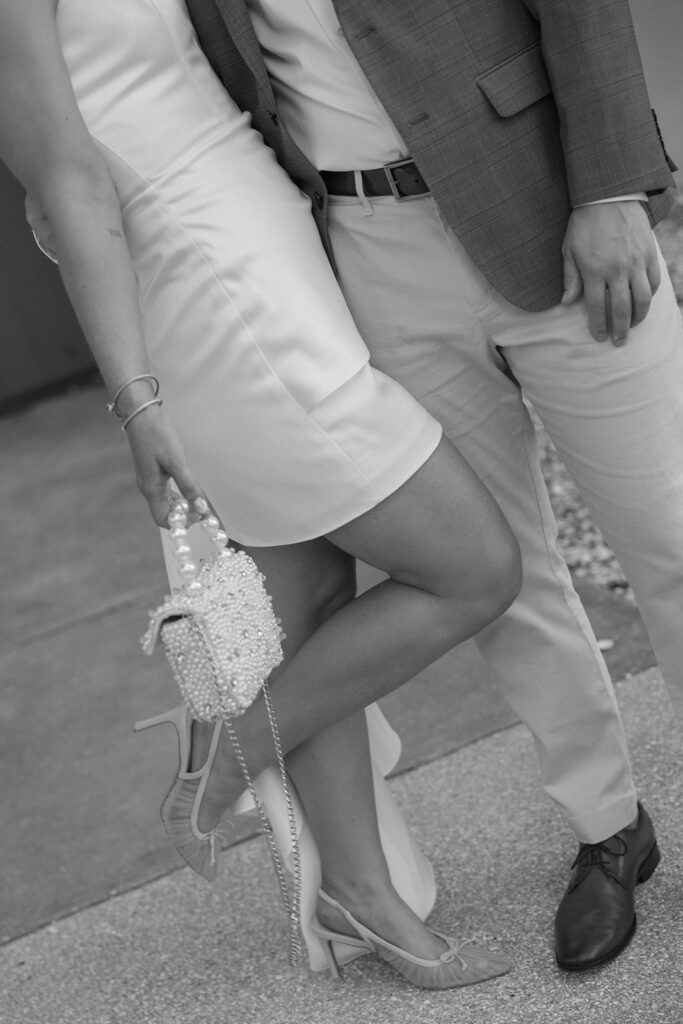 Black and white detail of the bride and groom's hands with a pearl-beaded clutch, St. Augustine wedding day