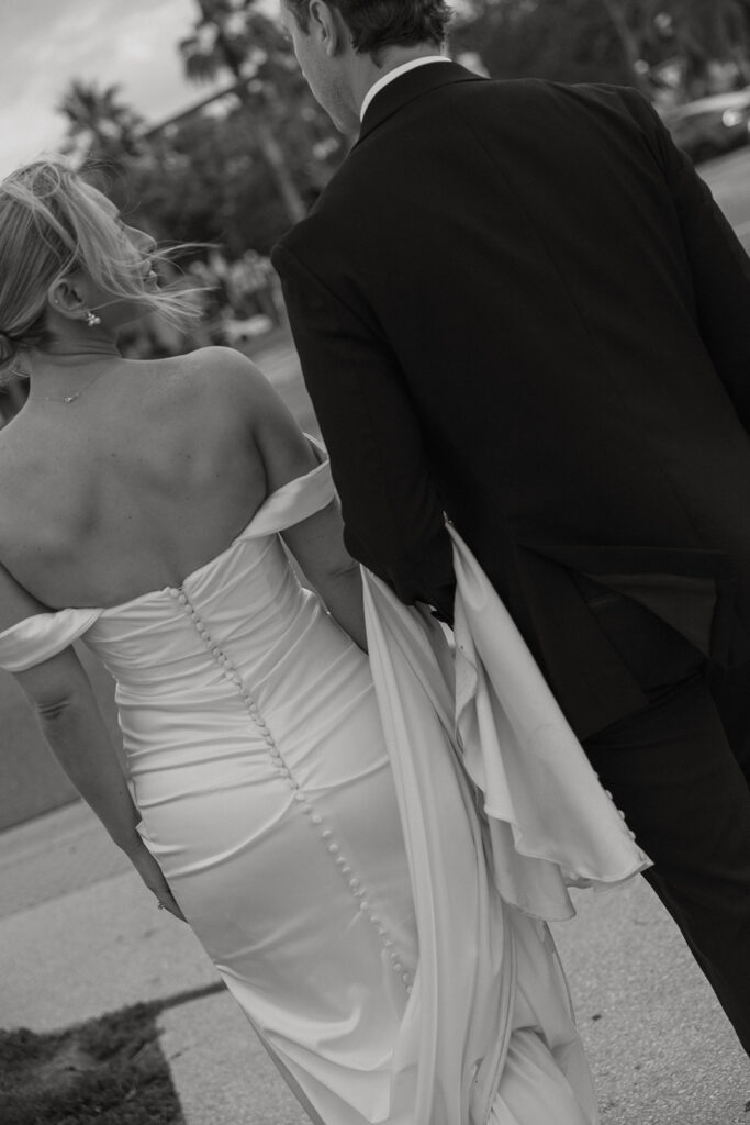 Black and white photo of the bride's gown detail as she walks with the groom, St. Augustine wedding