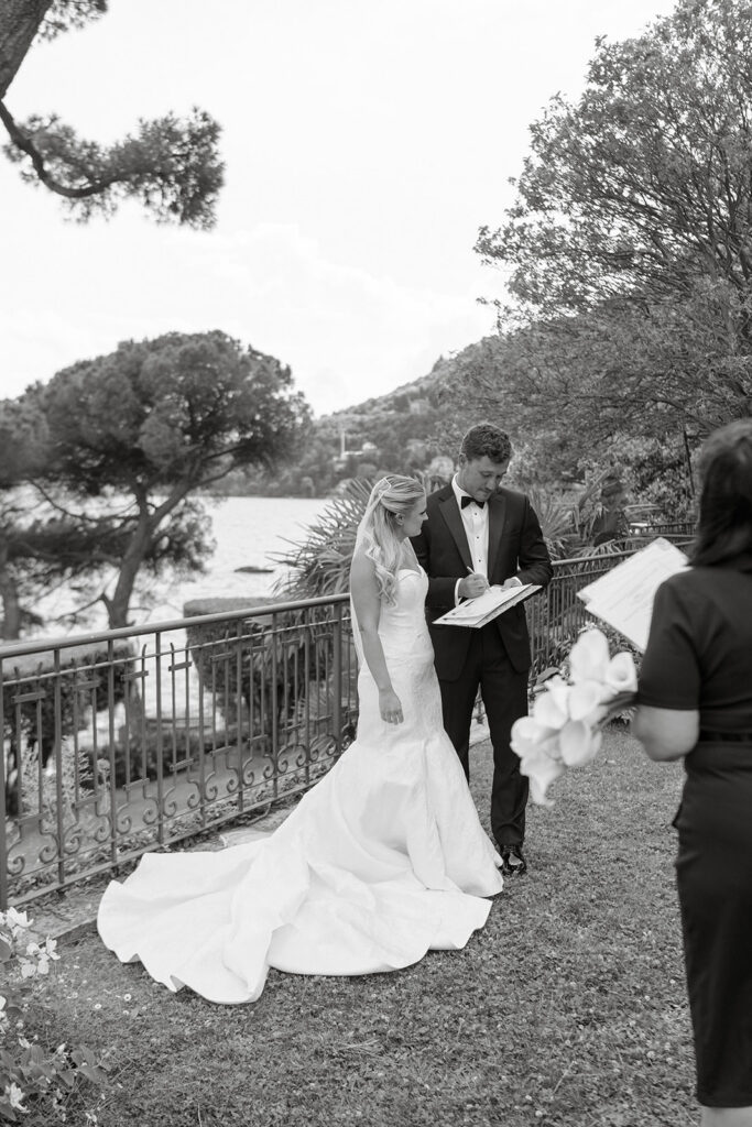 Black and white vow exchange by Lake Como with officiant in the background
