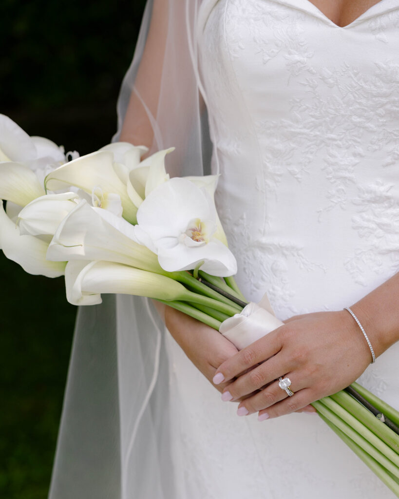 Bride's hand holding a white calla lily bouquet, close-up detail