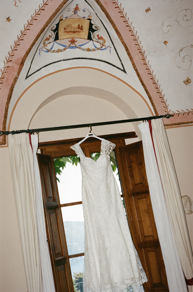Wedding gown hanging in a frescoed doorway with an ocean view