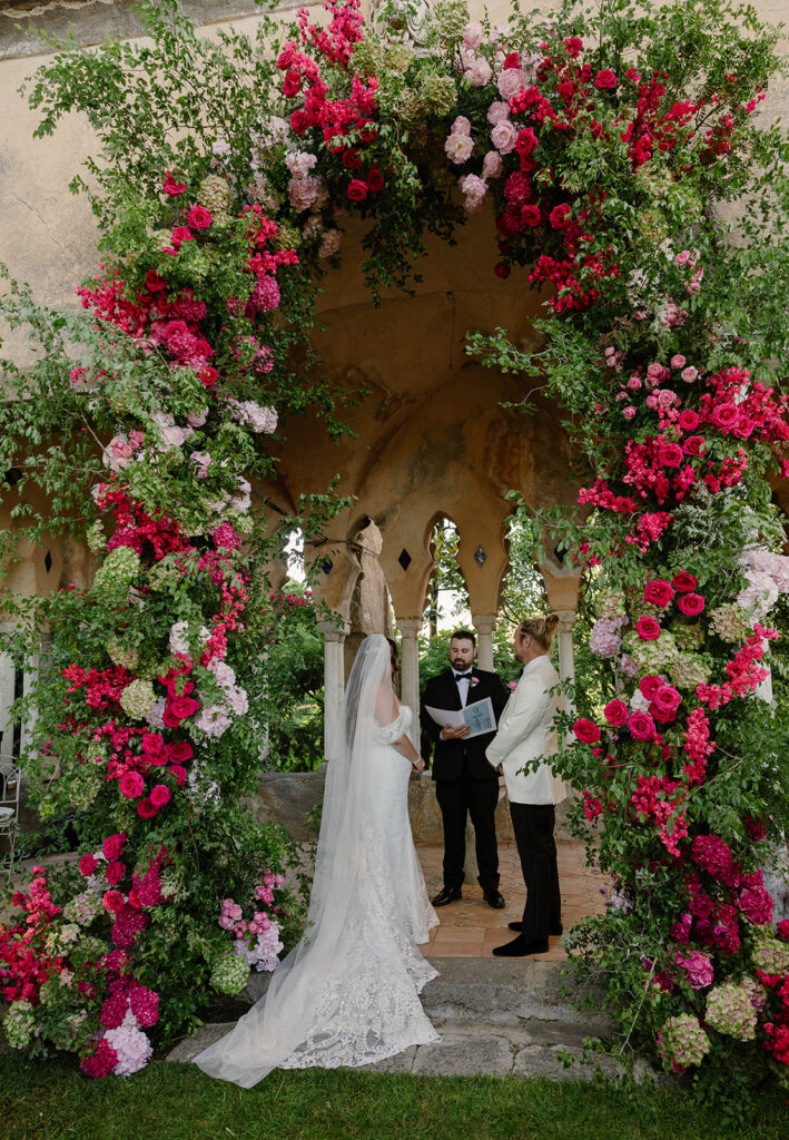 Bride and groom exchanging vows under a floral arch at Villa Cimbrone