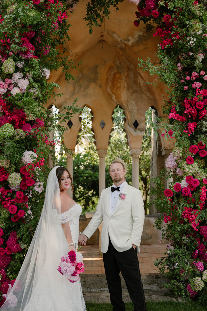 Bride and groom exchanging vows under a rose-covered stone alcove, Villa Cimbrone wedding ceremony
