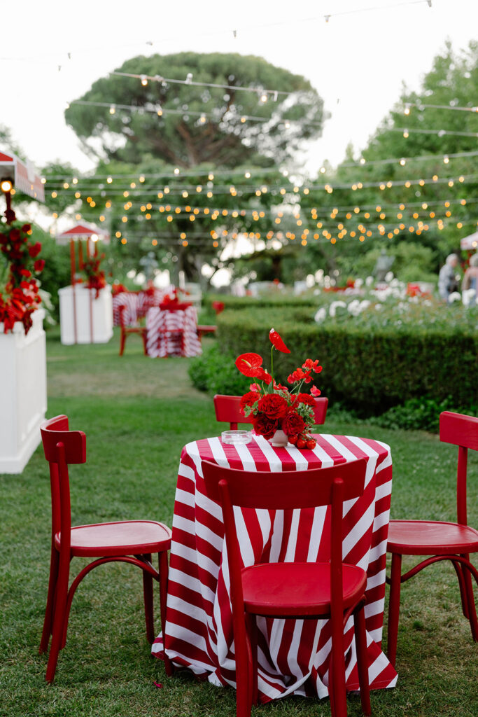 Red and white striped reception tables strung with lights at dusk, Villa Cimbrone wedding