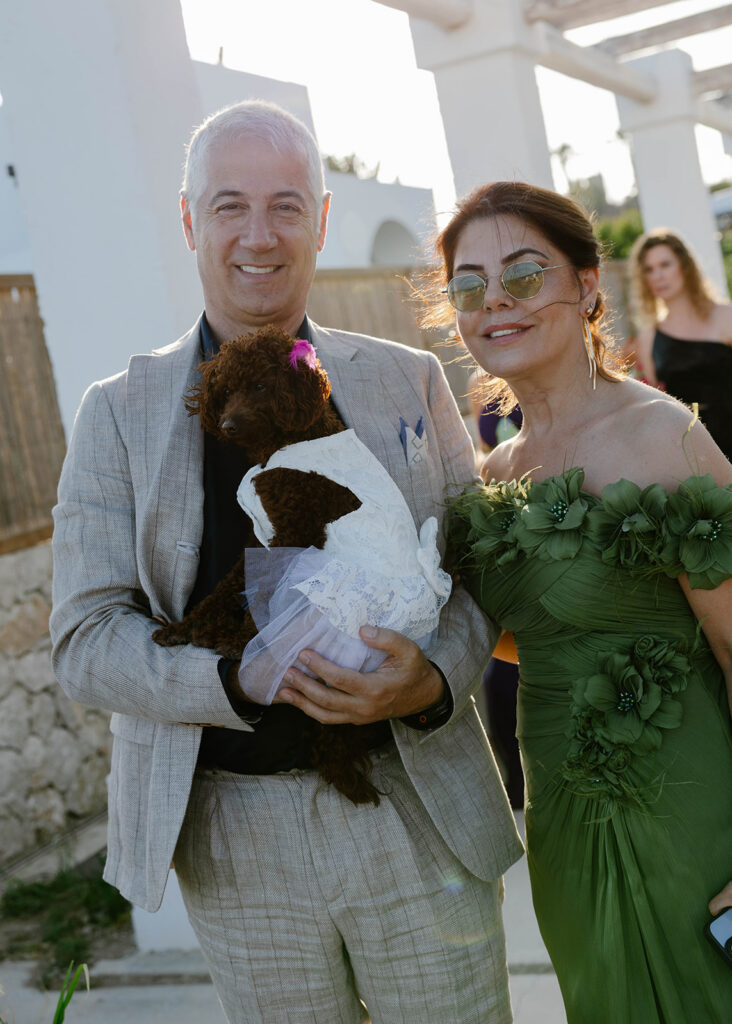 Guests holding a small white dog with a pink bow at the Rhodes wedding