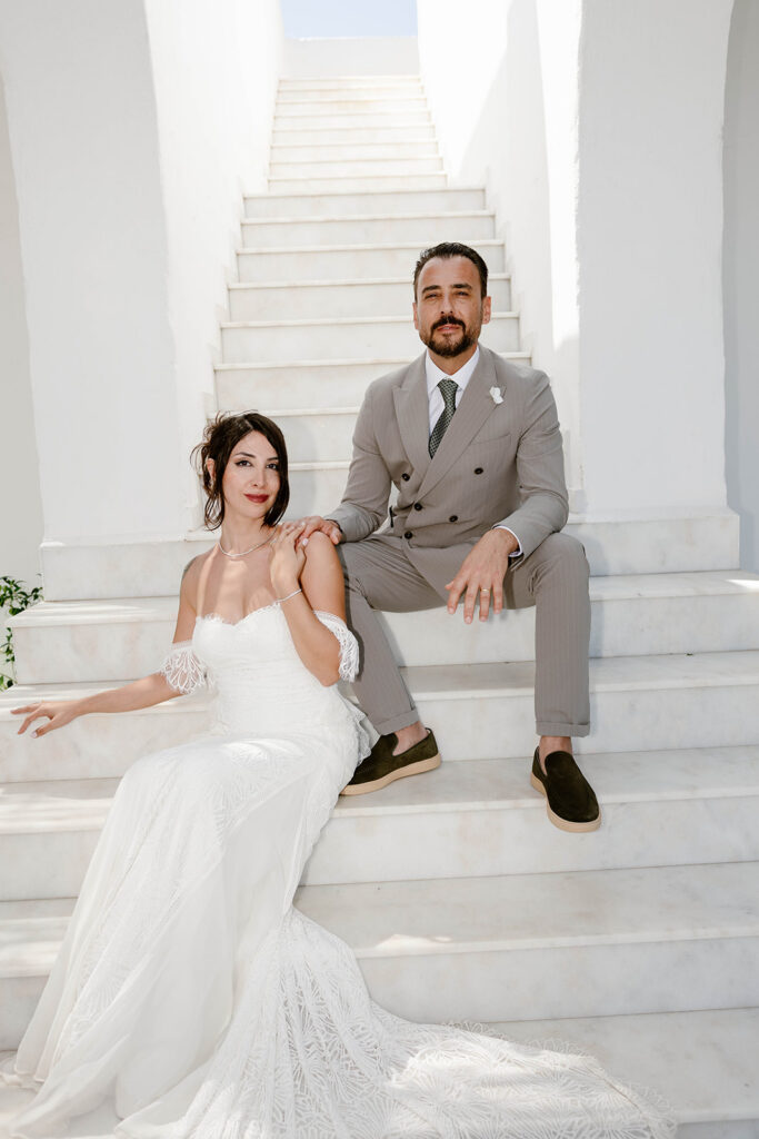 Bride and groom seated together on white steps, intimate Rhodes wedding portrait