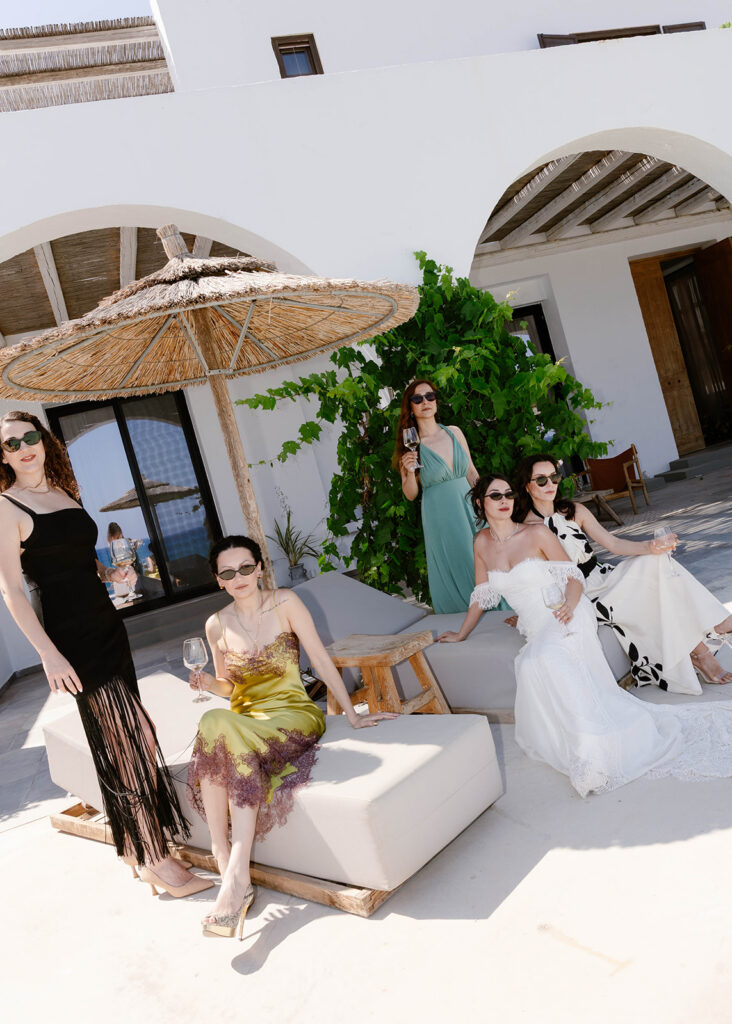 Bridesmaids in colorful gowns lounging on a patio before the Rhodes wedding