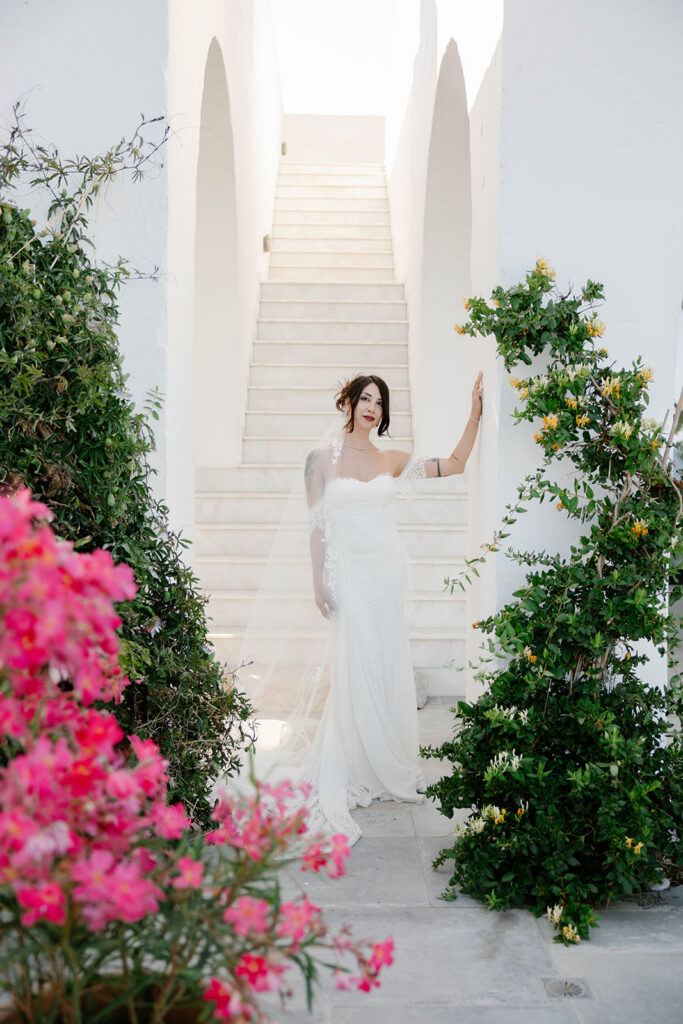 Bride walking up white steps beside pink bougainvillea, Rhodes, Greece
