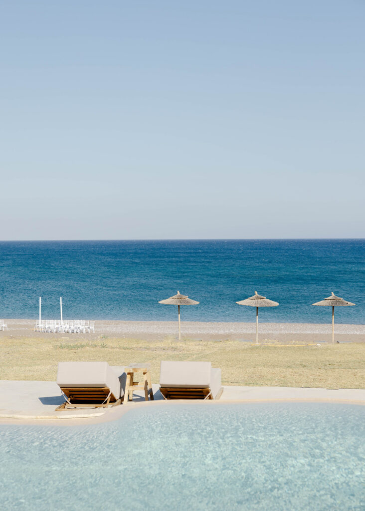 Blue sea and striped beach umbrellas along the Rhodes, Greece coastline