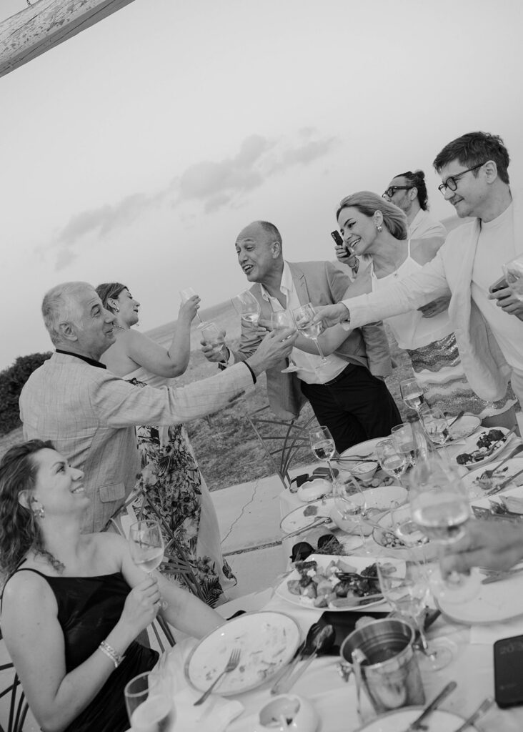 Guests toasting together at the reception table, black and white