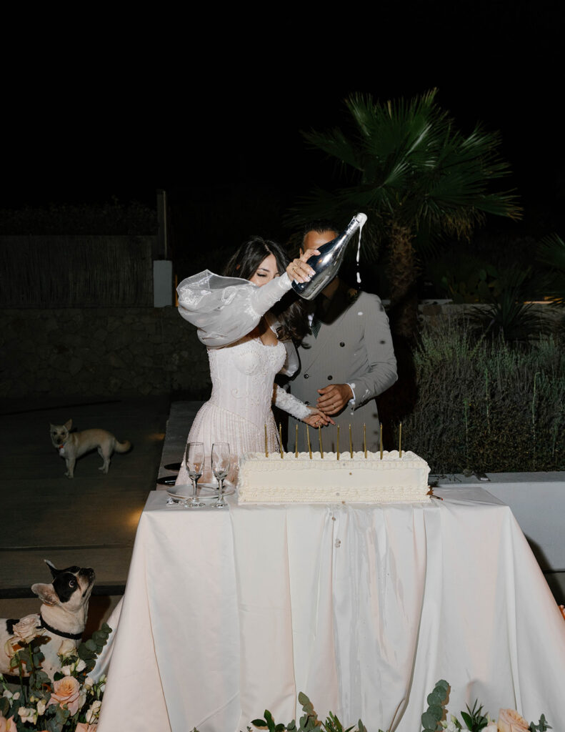Bride and groom cutting their wedding cake together at night