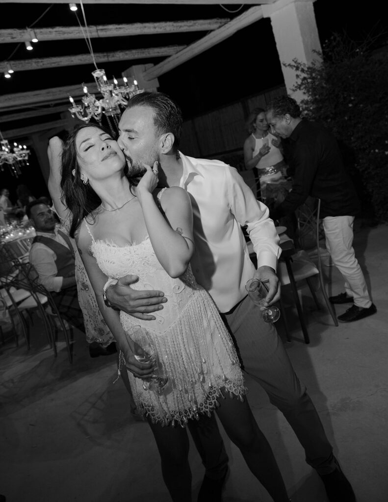 Groom kissing the bride's cheek on the dance floor, black and white