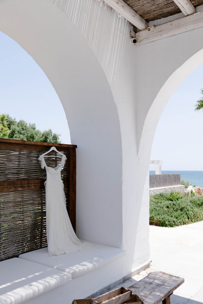 Wedding gown hanging in a whitewashed archway with ocean views, Rhodes wedding